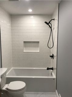 a white toilet sitting next to a bath tub in a bathroom under a shower head