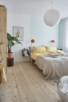 a bed room with a neatly made bed and a potted plant in the corner