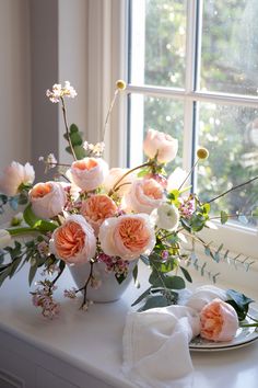 a vase filled with pink and white flowers next to a window