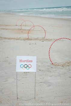 a sign that is on the sand by some water and two rings in the sand