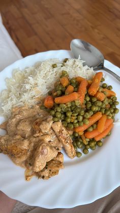 a white plate topped with meat, rice and veggies next to a spoon