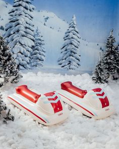 two red and white skis sitting in the snow next to some pine tree's