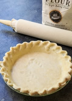 an uncooked pie crust sitting on top of a table next to a rolling dough roller