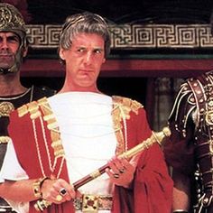 two men dressed in roman costumes standing next to each other with swords and armor around their necks