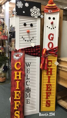 two snowmen made out of shutters with red and yellow ribbons on each side