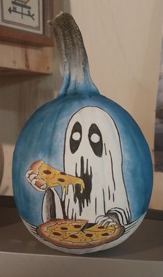 a painted pumpkin with a ghost eating pizza