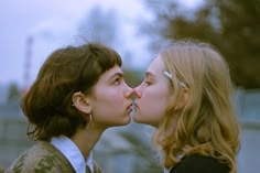 two young women are kissing each other outside