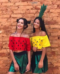 two young women wearing matching outfits standing next to each other in front of a brick wall