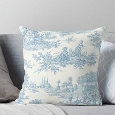 a blue and white toiler print pillow on a gray couch with two pillows