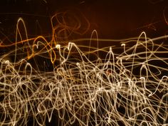 blurry photograph of light streaks in the night sky, with orange and yellow lights