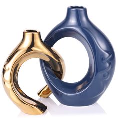 two gold and blue vases sitting next to each other on a white table top