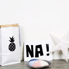 two bags and a pillow sitting on the floor next to each other, one with a pineapple painted on it