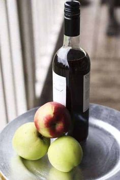 a bottle of wine and two apples on a plate