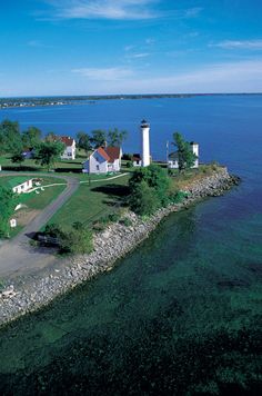 an aerial view of the lighthouses and houses on the water's edge, with blue skies in the background