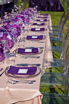 the table is set with purple flowers and place settings for an elegant dinner or party