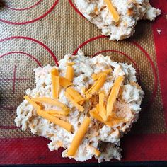 two crackers with cheese on them are sitting on a red mat next to each other