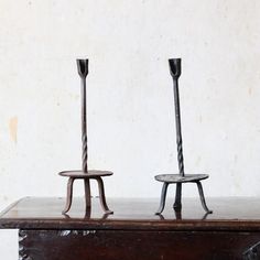 two metal candlesticks sitting on top of a wooden table