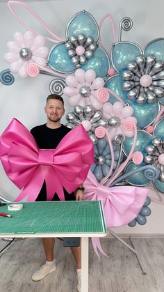 a man standing in front of a table with a large pink bow on it