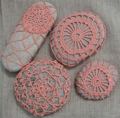 four crocheted rocks sitting next to each other on a gray cloth covered surface