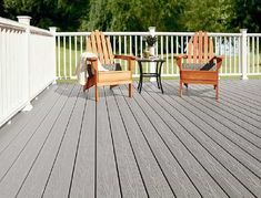 two wooden chairs sitting on top of a wooden deck next to a table and chair