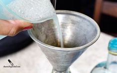 a person pouring water into a silver cup