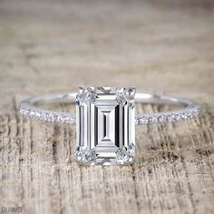 an emerald cut diamond ring with diamonds around it