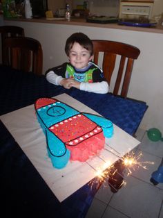 a young boy sitting at a table with a birthday cake