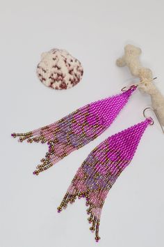 Have you heard the mermaids calling? Our new mermaid tail seed bead earrings are calling to you. Add a touch of magic to your day with our hand beaded earrings with iridescent bright colors and jeweled fins. Made with premium delica seed beads and gold filled or sterling silver ear wires. The purple ones come with sterling silver ear wires, while all the other colors come with gold filled ear wires can swap silver to gold or vice versa. Just message us. Available in 8 colors-Aqua, Purple, Green, Handmade Mermaid Earrings For Gift, Handmade Purple Beaded Earrings For Beach, Purple Beaded Dangle Earrings For Beach, Purple Dangle Beaded Earrings For Beach, Pink Mermaid Tail, Handmade Beaded Earrings, Beach Lover Gifts, Mermaid Earrings, Pink Mermaid