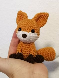 a hand is holding a small knitted fox