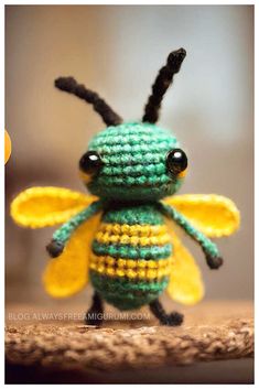 a small green and yellow crocheted bee sitting on top of a wooden table