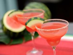 watermelon and cucumber margaritas are served in coupe glasses on a red tablecloth