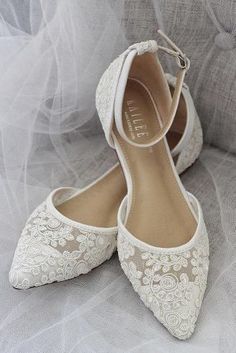 white wedding shoes with lace on the toes and heels are sitting on a gray couch