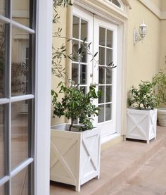 two white planters sitting on the side of a building next to an open window