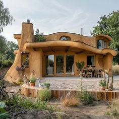 an unusual house in the middle of a field with lots of plants and trees around it