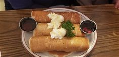 two burritos on a plate with sauce and ketchup are sitting on the table