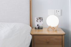 a white lamp sitting on top of a wooden night stand