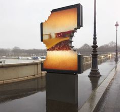 a large sign on the side of a road next to a street light and lamp post