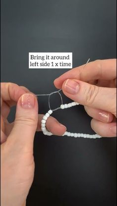 two hands are holding beads and threading the string to make a bead bracelet