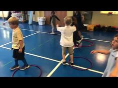 two young boys are playing with hula hoops on the floor in an indoor gym