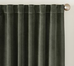 a green curtain hanging on the side of a window with a metal ball in front of it