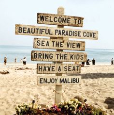 a wooden sign sitting on top of a sandy beach