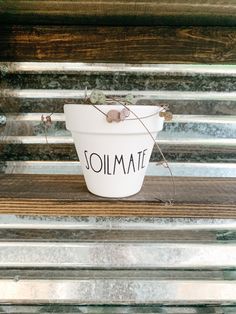 a white bucket with the word soilmate written on it sitting on a wooden bench