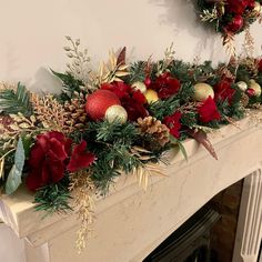 a mantel decorated with christmas decorations and greenery on top of a fireplace mantle