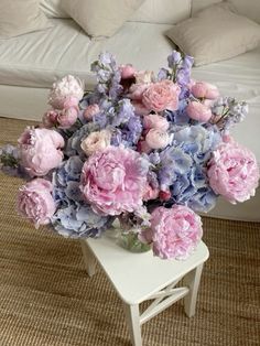 a vase filled with pink and blue flowers on top of a white table next to a couch