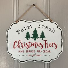 a christmas tree sign hanging from the side of a door with pine trees on it