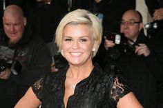 a woman with blonde hair is smiling for the camera as she stands in front of photographers