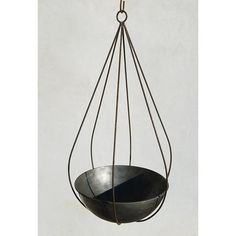 a metal bowl hanging from a hook on a white wall with no one in it