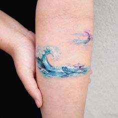 a woman's arm with an ocean wave tattoo on the left side of her body