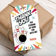 a thank you card with a bowling ball and skis on it, next to a wrapped gift box