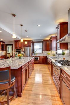 a large kitchen with wooden cabinets and marble counter tops, along with hardwood flooring